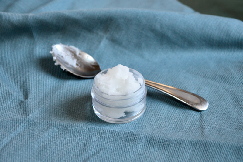 coconut oil in container on blue cloth with spoon