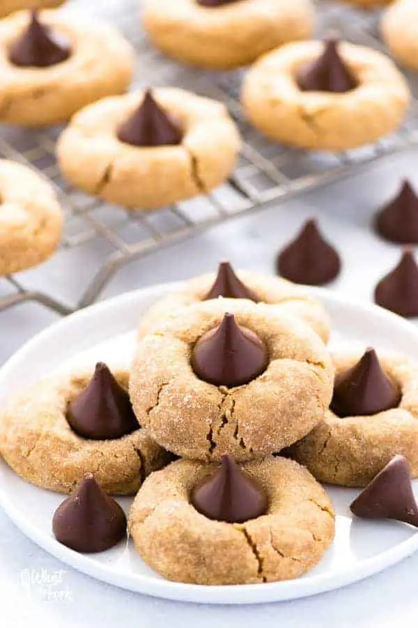 gluten-free peanut butter blossoms on plate  on white counter with extra chocolate kisses