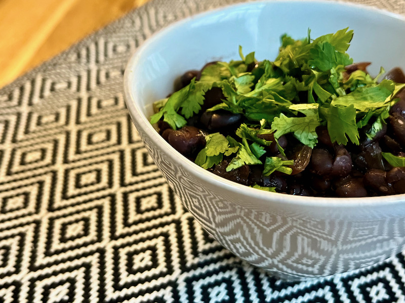 Instant Pop black beans in white bowl on black and white placemat